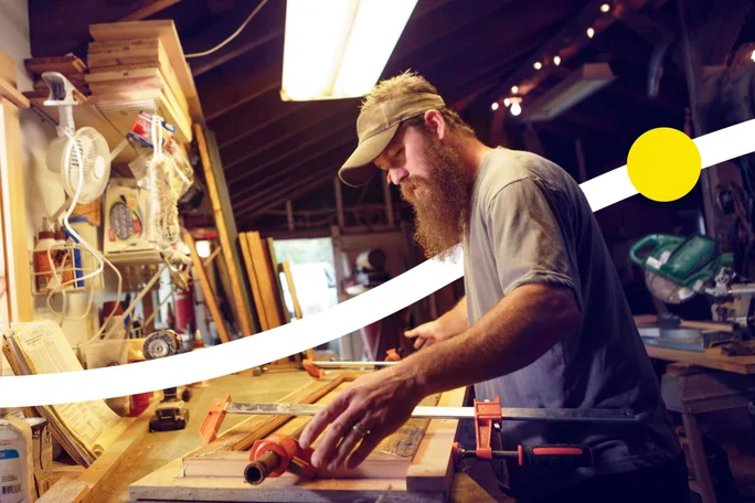 Ein Handwerker mit Bart arbeitet in einer Werkstatt an einem Holzprojekt