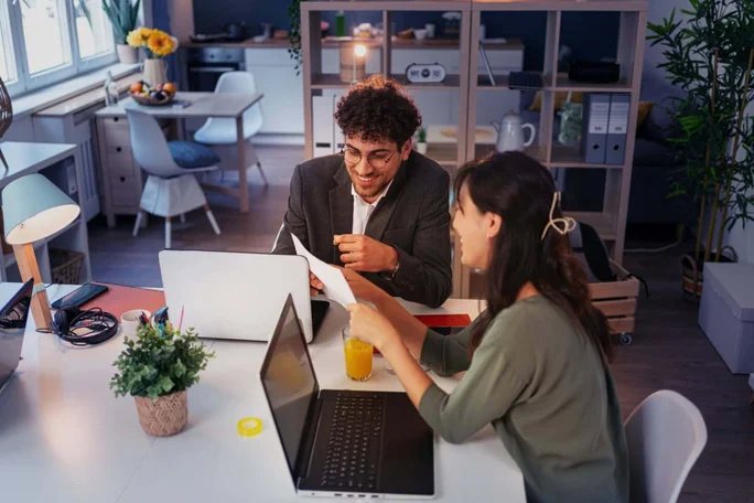 Ein Team diskutiert in einem modernen Büro mit Laptops und Dokumenten. Effiziente Zusammenarbeit für erfolgreiche Ergebnisse. Auri Kontaktseite Privatkunden.